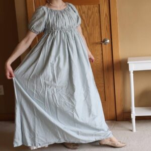 Woman wearing long pale blue dress with puffed sleeves and empire waist